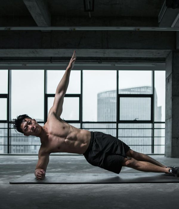 Man performing a stability strength exercise in a dark gym setting